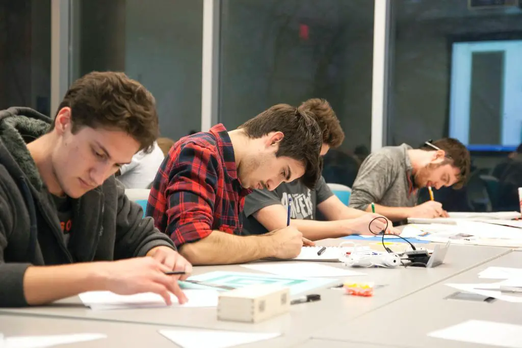 Group of students taking notes or taking a test on the desks during lecture