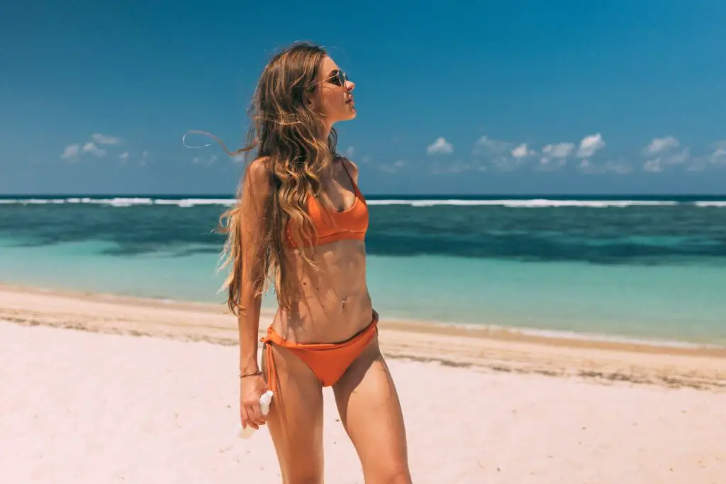 Woman in Orange Bikini Looking Away on the beach in Florida.