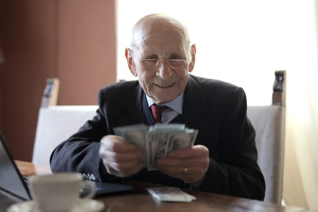 Law as business, an aged lawyer in suit holding money in his hands in the office